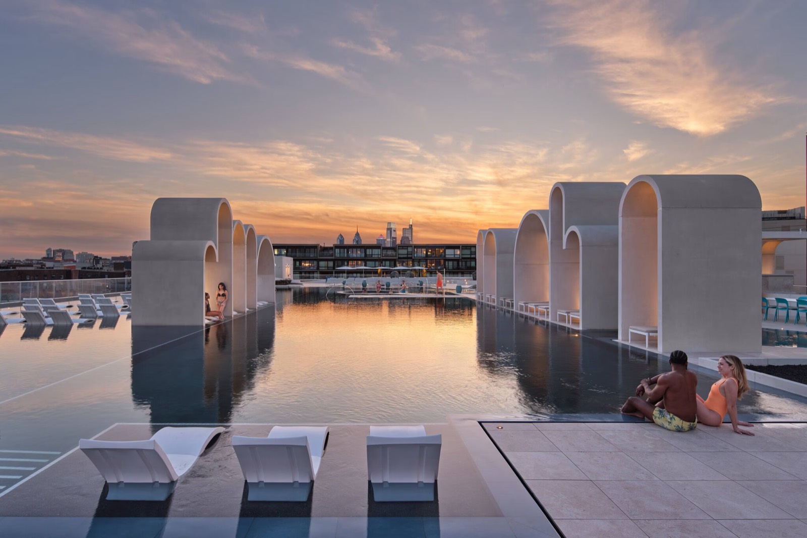 Arched rooftop infinity pool at sunset with the Philadelphia skyline